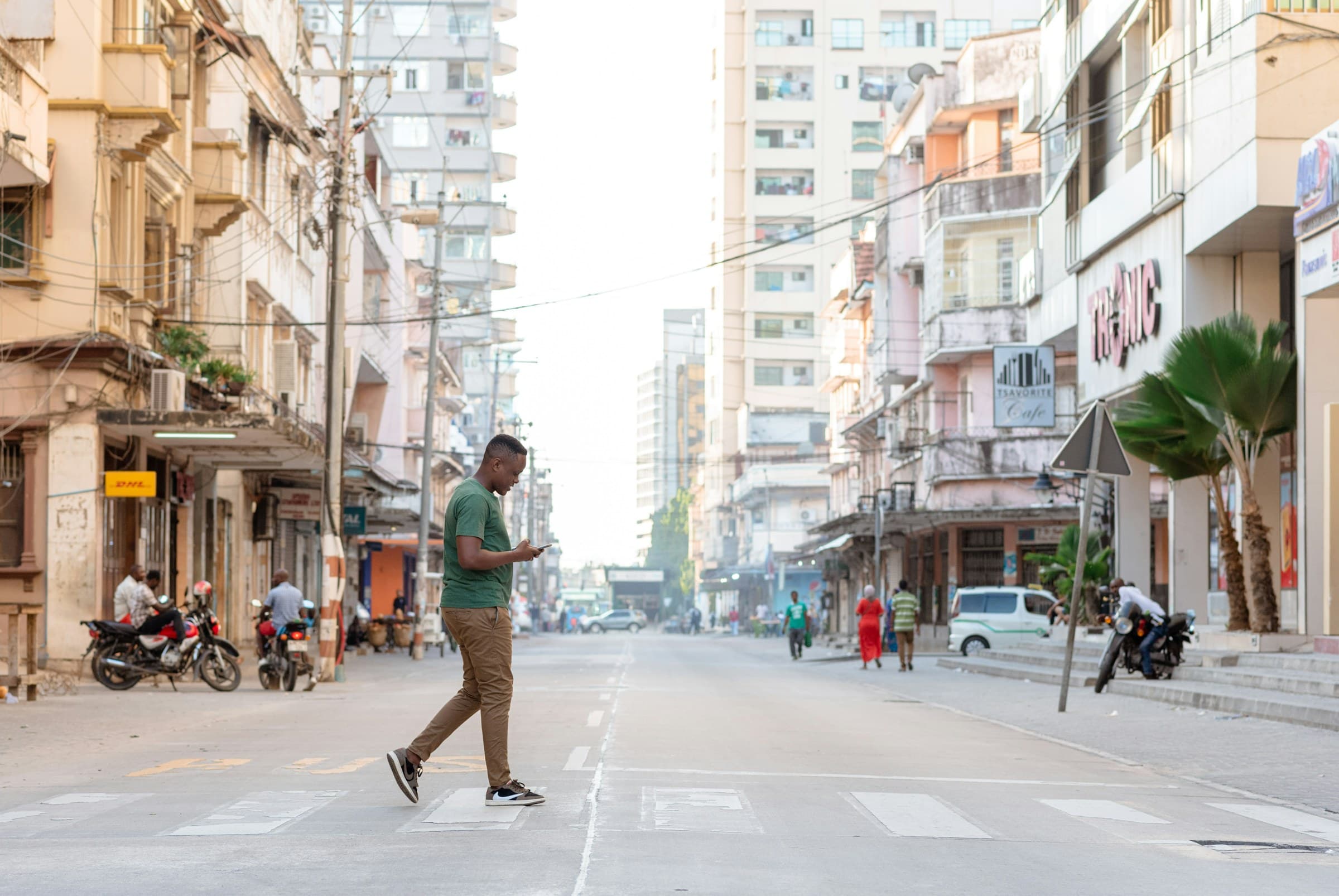 A young man checking his phone while crossing a street in Dar es Salaam